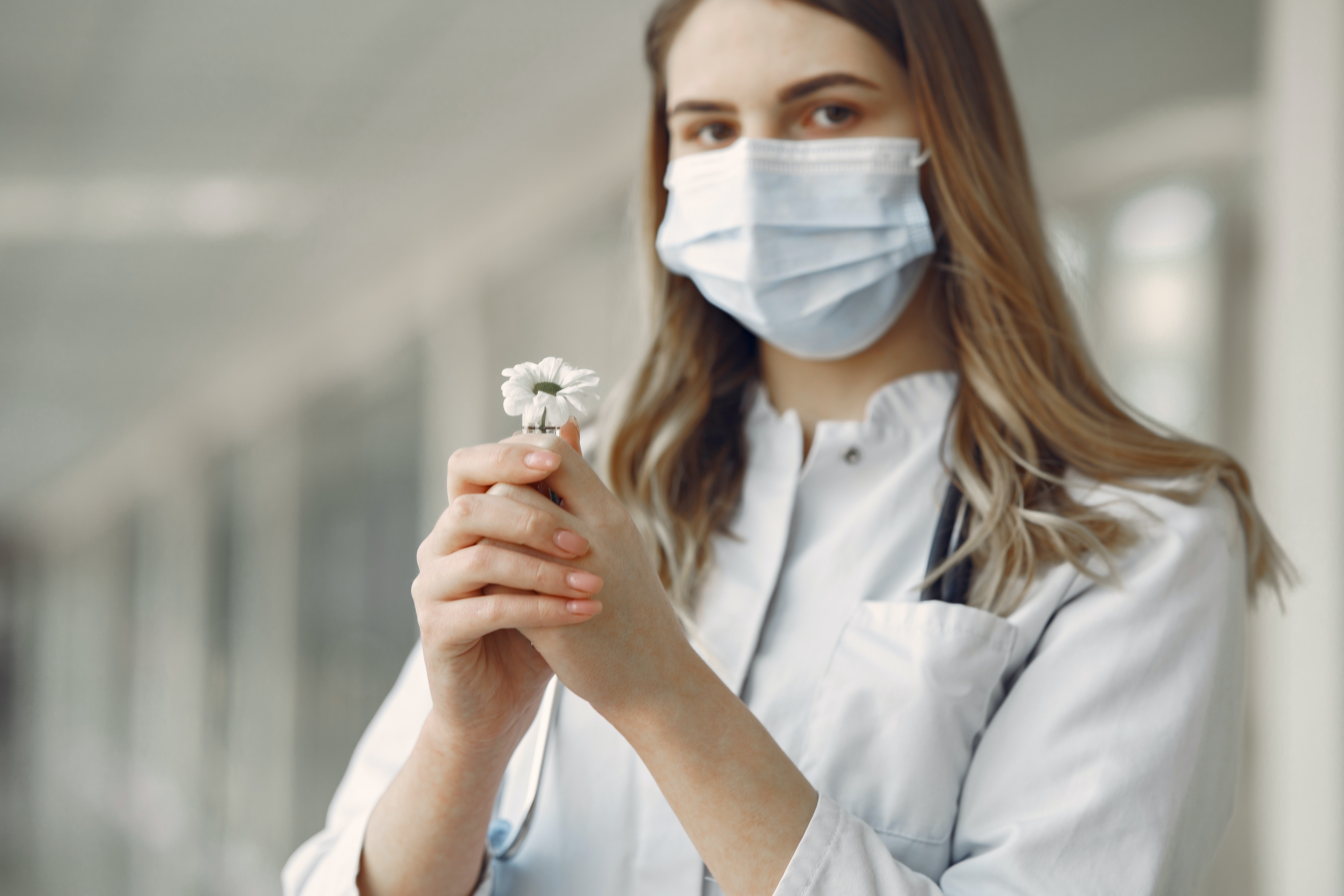 woman with face mask and holding flower